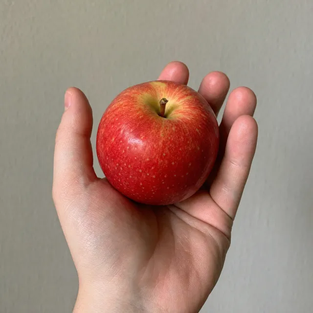 A realistic photo of a hand holding a red apple, with all fingers clearly visible. - GPT Image 2