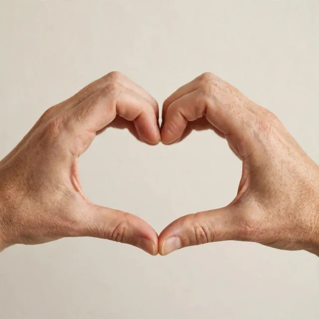 Two hands forming a heart shape together against a plain background. - Muse Image