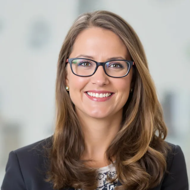 A professional headshot of a businesswoman wearing glasses, against a blurred background. - Flux 1.1 Pro Ultra