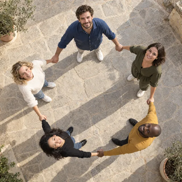 A group of five people joining hands in a circle, seen from above - Takumi 1.1