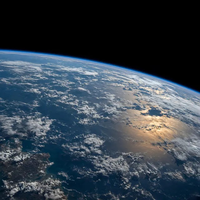 Photorealistic aerial photograph clearly showing the edge of the Earth from space, capturing realistic curvature, atmosphere, and sunlight reflections - Takumi 1.1