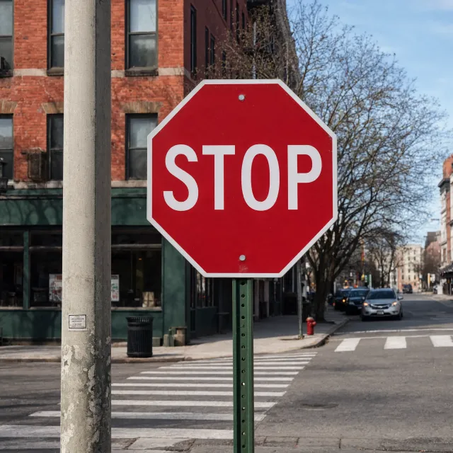 A red stop sign on a street corner displaying the word "STOP", photorealistic urban… - Reve 2.1