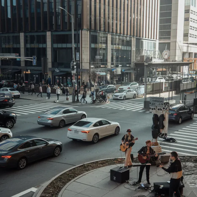 A busy city intersection with cars, pedestrians, and street performers all in one frame - Ideogram V2