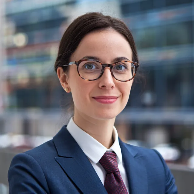 A professional headshot of a businesswoman wearing glasses, against a blurred background. - Ideogram V2