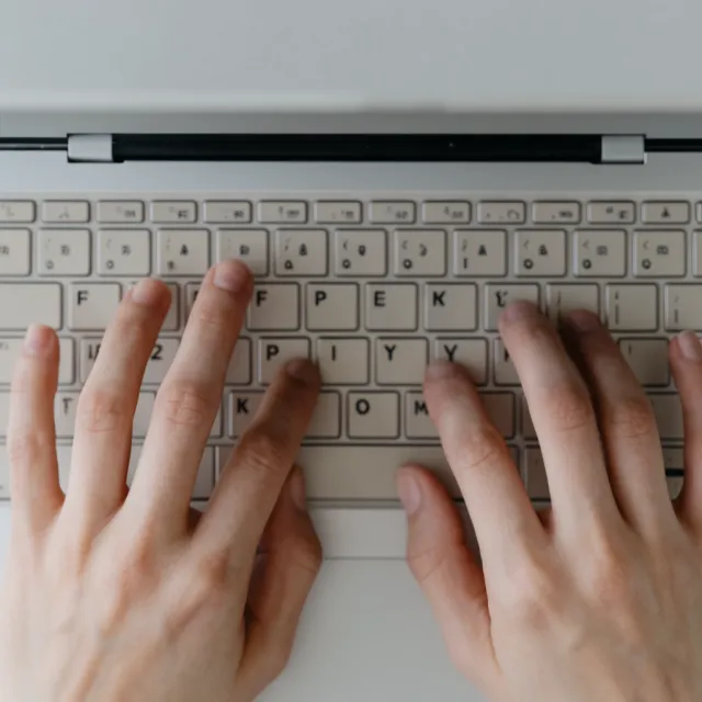 A person typing on a laptop keyboard, showing both hands on the keys - Krea 2 Large