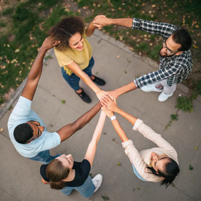 A group of five people joining hands in a circle, seen from above - Recraft V3