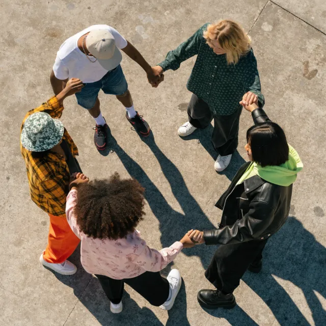 A group of five people joining hands in a circle, seen from above - Recraft V4.1