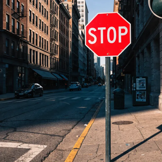 A red stop sign on a street corner displaying the word "STOP", photorealistic urban… - Recraft V4.1