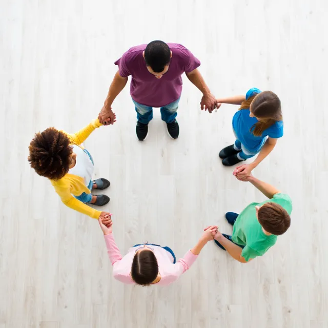 A group of five people joining hands in a circle, seen from above. - Reve Image (Halfmoon)