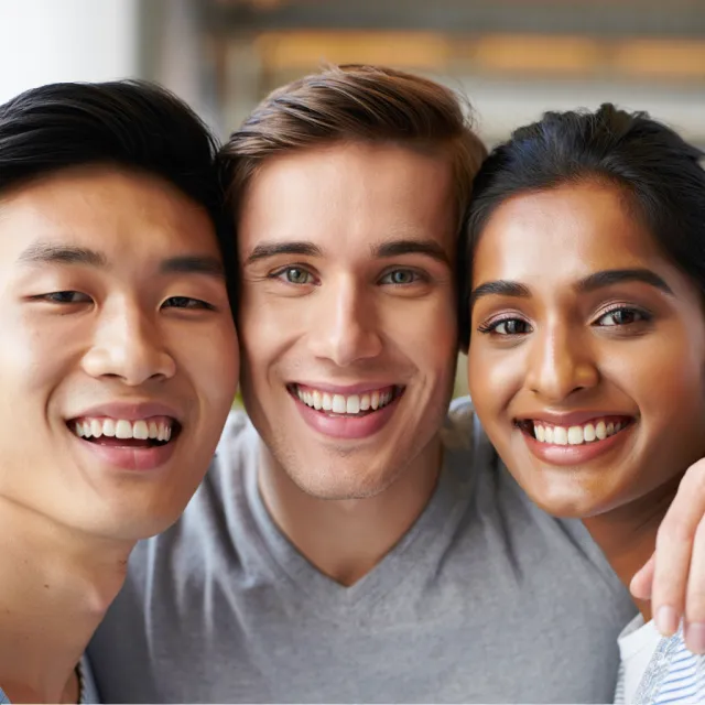 A group selfie of three friends of different ethnic backgrounds smiling at the camera - Reve Image (Halfmoon)