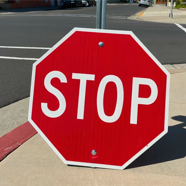A red stop sign on a street corner displaying the word "STOP", photorealistic urban… - Reve Image (Halfmoon)