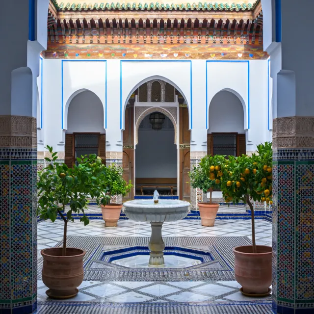 A traditional Moroccan riad courtyard with detailed zellige tilework, flowing fountain… - Reve Image (Halfmoon)